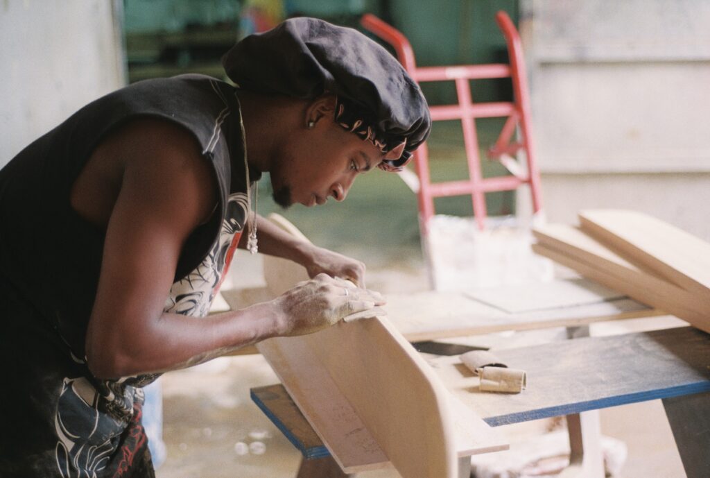 Handmade designer furniture production showing artisans sanding and polishing concrete and wood pieces.