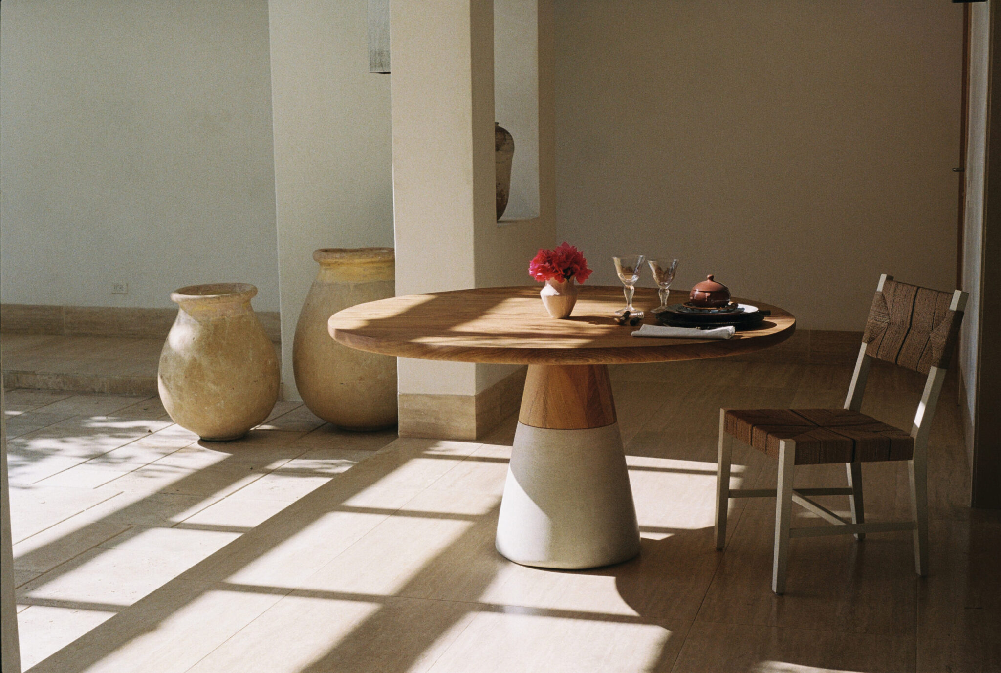 Bahia solid rosewood dining table with natural wood grain tabletop and sculptural white concrete and oak conical base.