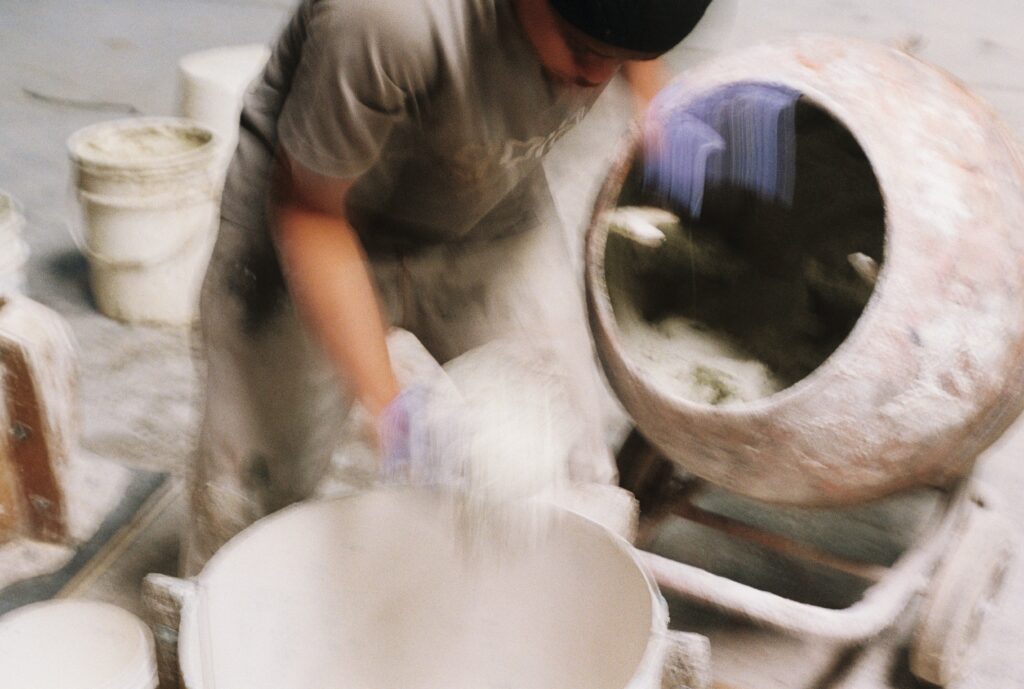 Custom concrete furniture making process with craftsmen refining surfaces by hand.