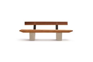 Banco B wooden bench by Gola Home, featuring diagonally cut wood slats, concrete block legs, and a wood backrest with metal supports, handcrafted in the Dominican Republic.