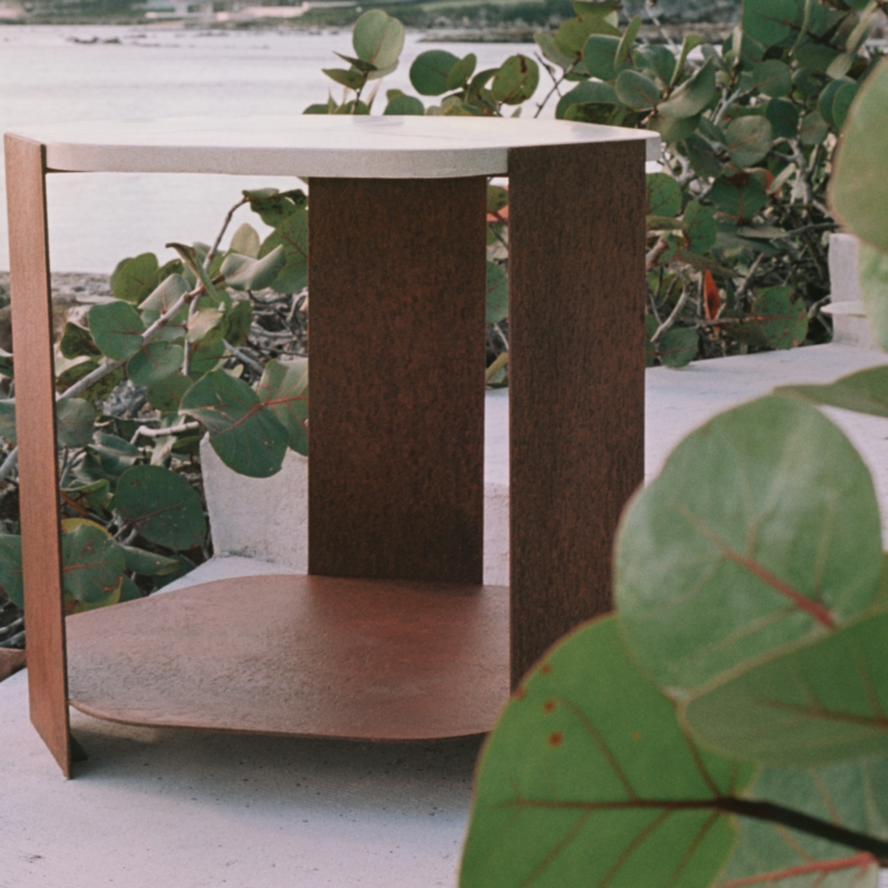 Ferro side table with hexagonal oxidized metal base in a bronze-orange tone and a beige concrete top with dark veining, sculptural statement table measuring 66 x 61 x 61 cm.