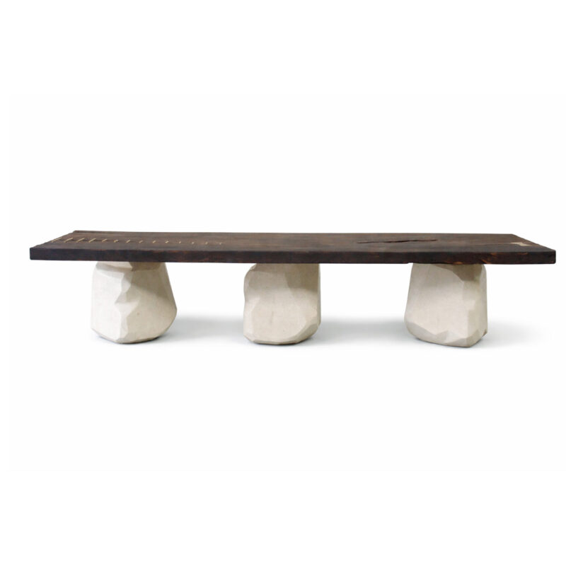 CAUTÚ coffee table with burnt wood top and bronze staples, supported by sculptural stone-like concrete bases, handcrafted by Gola Home in the Dominican Republic.