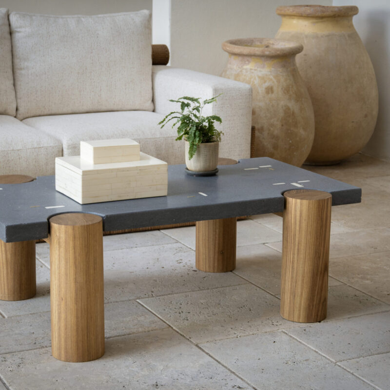CACIQUE coffee table with a rectangular concrete top inlaid with white concrete and bronze elements, supported by four solid Caribbean hardwood pillars.