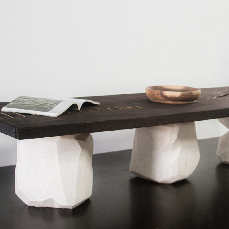 CAUTÚ coffee table with burnt wood top and bronze staples, supported by sculptural stone-like concrete bases, handcrafted by Gola Home in the Dominican Republic.