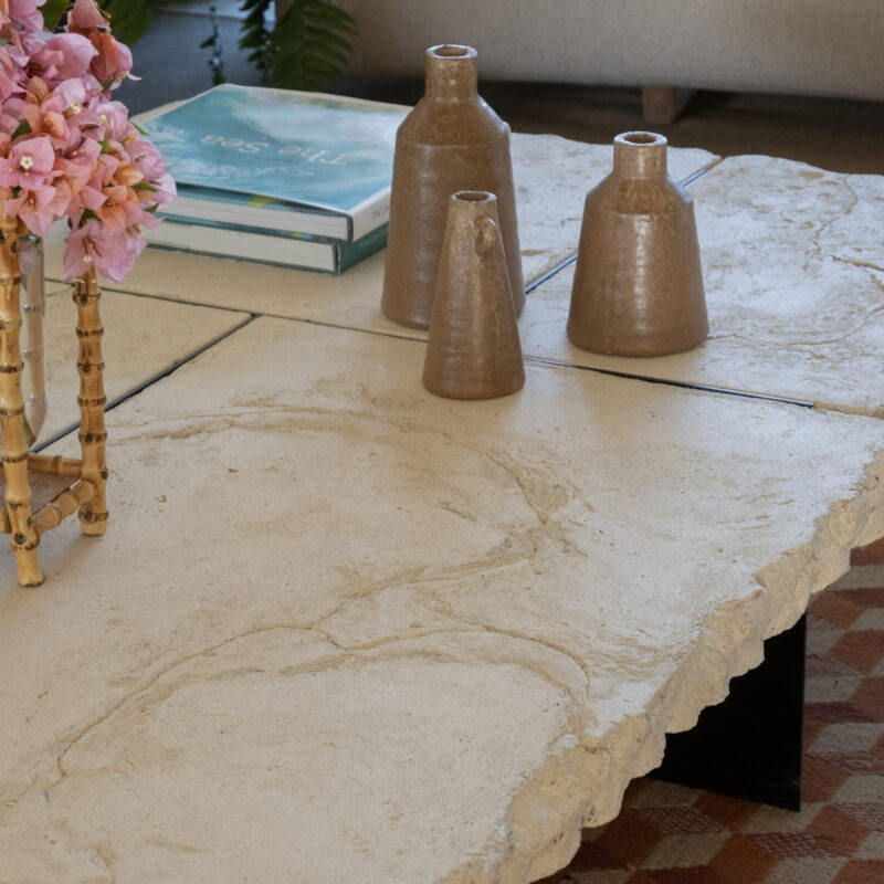 Raw white concrete coffee table with rock-like unpolished edges, separated slab top, and thin black iron base.